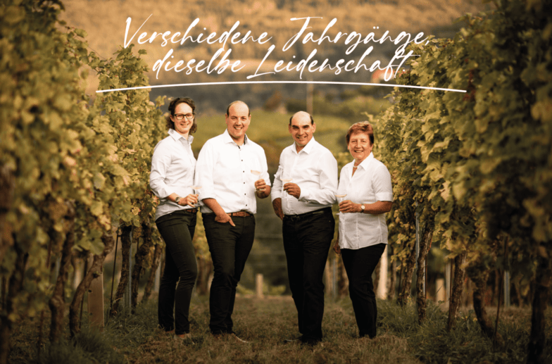 Verschiedene Jahrgänge, dieselbe Leidenschaft steht in weißer Schrift auf dem Bild. Von links nach rechts stehen Maria, Christoph, Josef und Herta im Weingarten mit einem Achterl Weißwein in der Hand