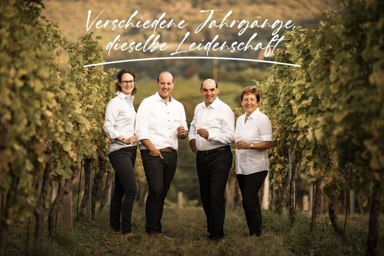 Familie_1 Verschiedene Jahrgänge, dieselbe Leidenschaft steht in weißer Schrift auf dem Bild. Von links nach rechts stehen Maria, Christoph, Josef und Herta im Weingarten mit einem Achterl Weißwein in der Hand